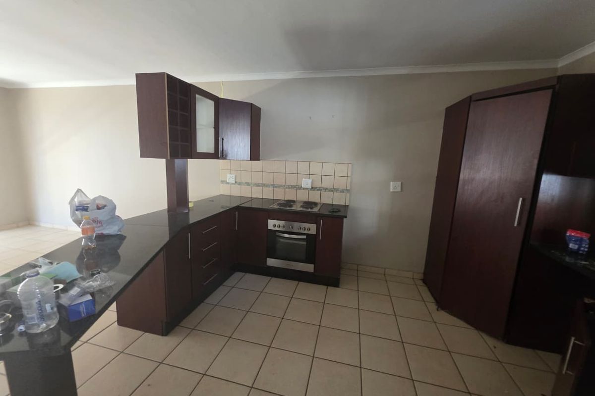A functional kitchen featuring dark wood cabinetry, granite countertops, a built-in oven and hob, and tiled flooring, offering a practical layout for daily use.