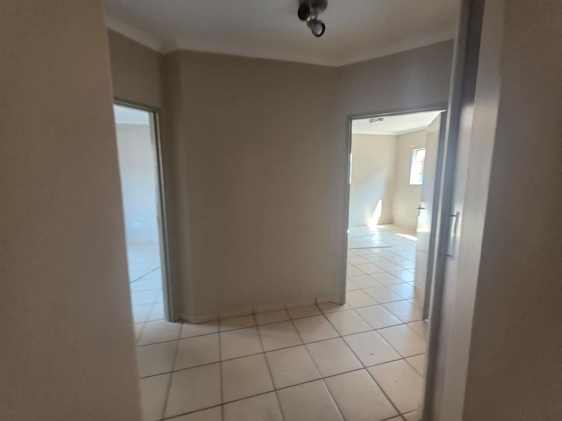A neutral-toned hallway featuring tiled flooring and access to adjacent rooms, providing a clean and functional transition space within the apartment.