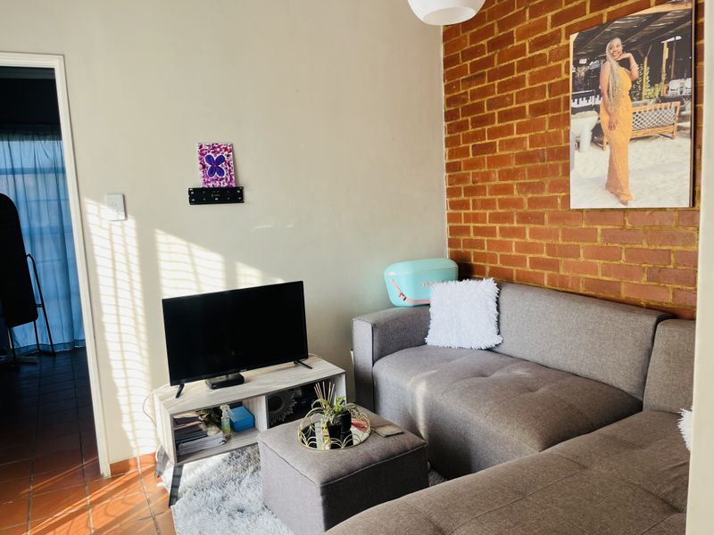 A living room area featuring an exposed brick feature wall and tiled flooring, providing a warm and textured aesthetic.