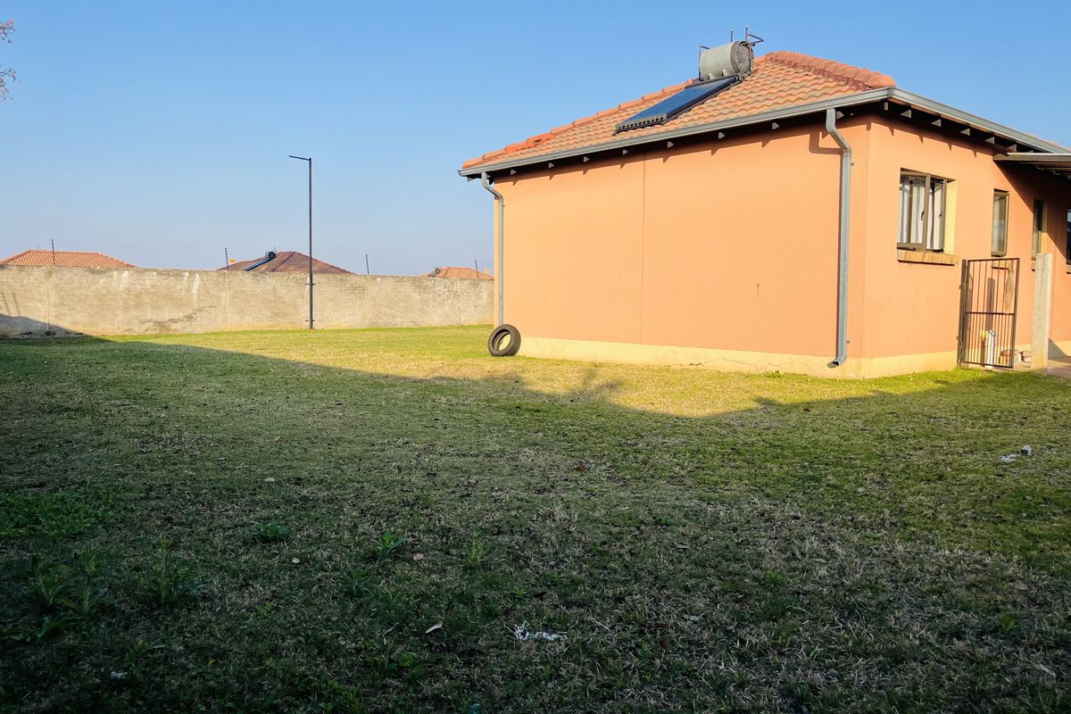 A view of the rear garden and side elevation of the townhouse, featuring a solar water heater and perimeter boundary wall.