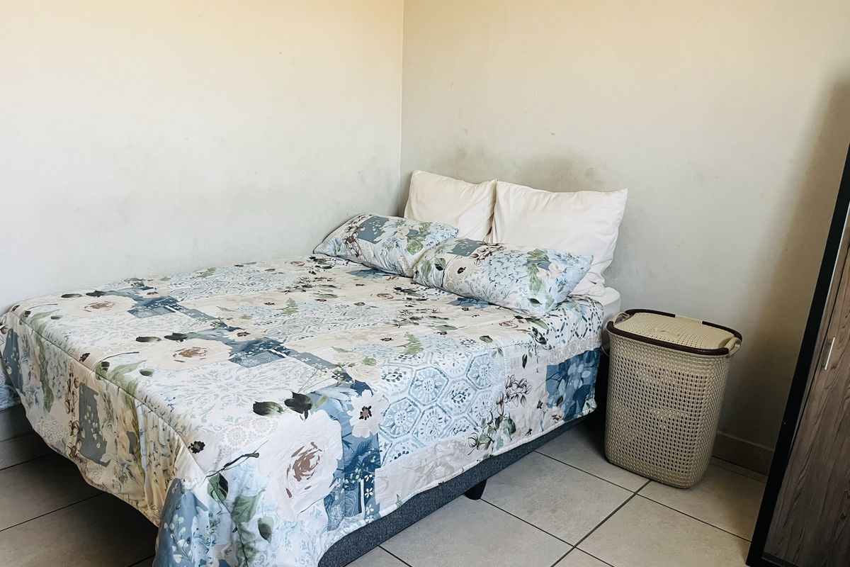A bedroom featuring tiled flooring and visible wall staining, requiring maintenance and cosmetic updates.
