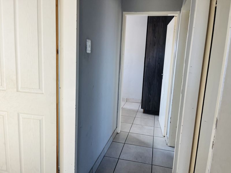 A functional hallway featuring tiled flooring and access to adjacent rooms with built-in storage.