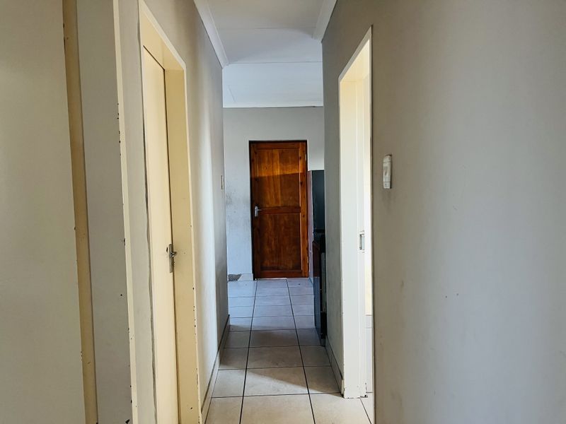 A functional hallway featuring tiled flooring and neutral walls, providing access to adjacent rooms within the townhouse.