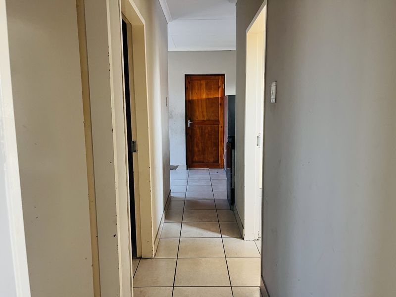 A functional hallway featuring tiled flooring and a timber door, connecting various rooms within the townhouse.
