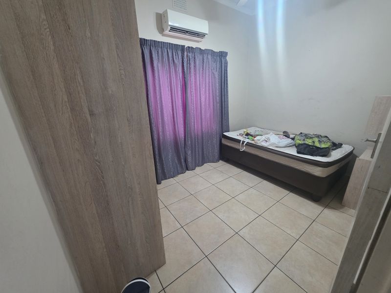A functional bedroom featuring ceramic floor tiles, a built-in wardrobe, and a wall-mounted split-system air conditioner.