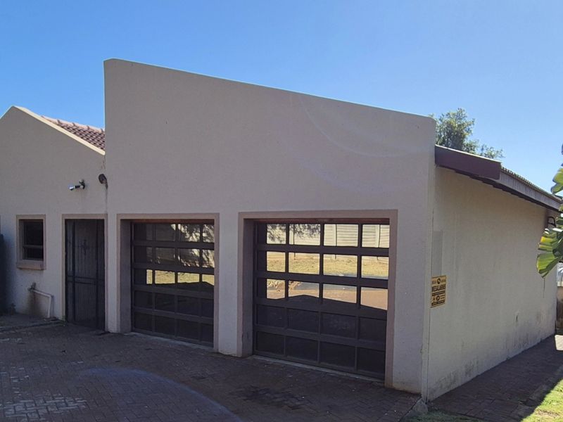 A detached double garage featuring modern glass-panelled doors, a paved driveway, and an integrated water storage tank.
