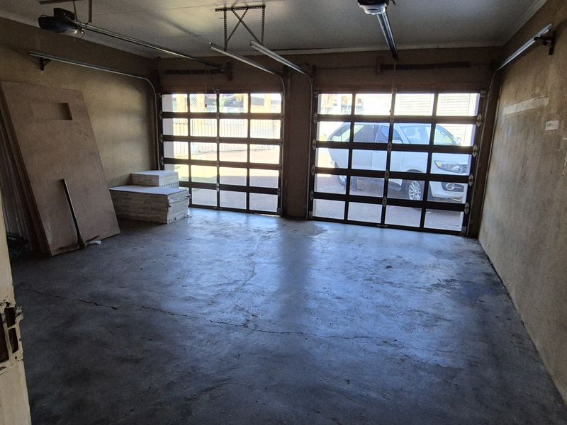 A spacious double garage featuring concrete flooring and two sectional garage doors, offering ample storage or parking space.