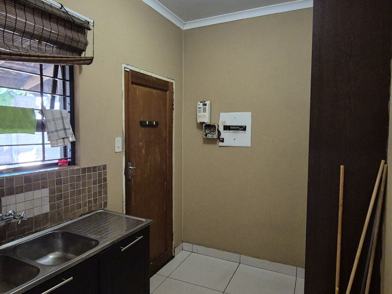 A functional laundry area featuring a double stainless steel sink, tiled splashback, and dedicated plumbing connections, ready for appliance installation.