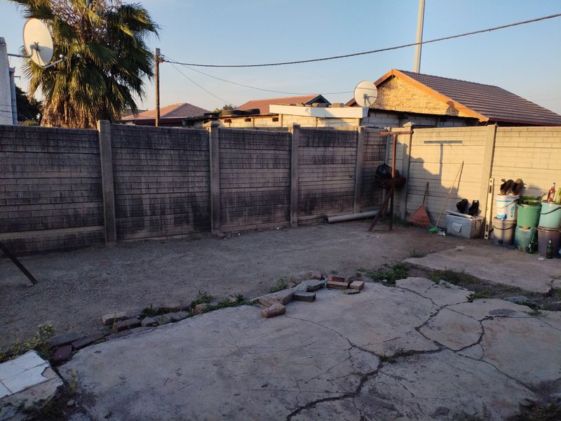 A rear outdoor area featuring a precast concrete boundary wall and a cracked concrete patio surface in need of maintenance.