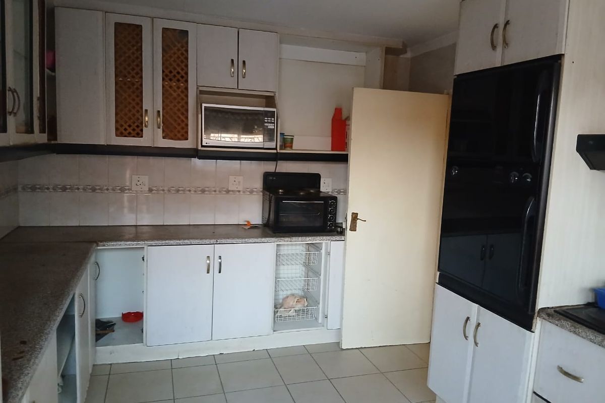 A dated kitchen featuring built-in cabinetry, tiled backsplash, and integrated oven, offering potential for modernization and layout optimization.