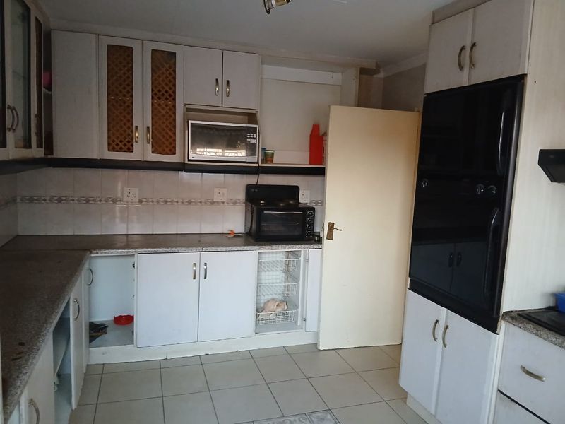 A dated kitchen featuring built-in cabinetry, tiled backsplash, and integrated oven, offering potential for modernization and layout optimization.