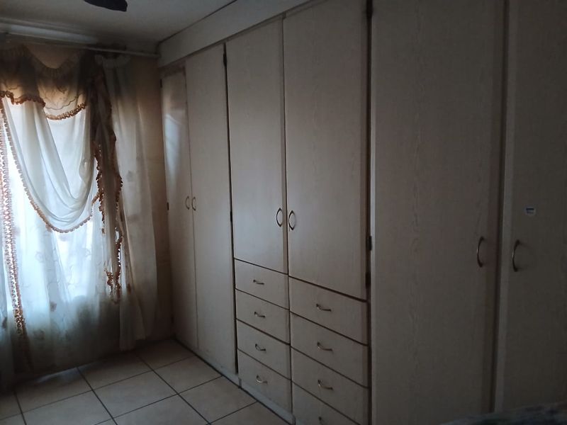 A bedroom featuring extensive built-in cupboards with integrated drawers and tiled flooring.