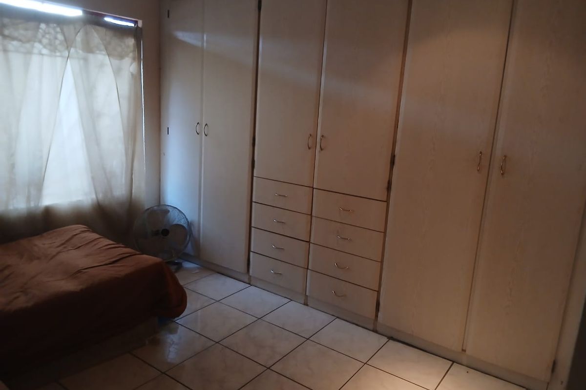 A bedroom featuring extensive built-in cupboards and tiled flooring, offering practical storage space.