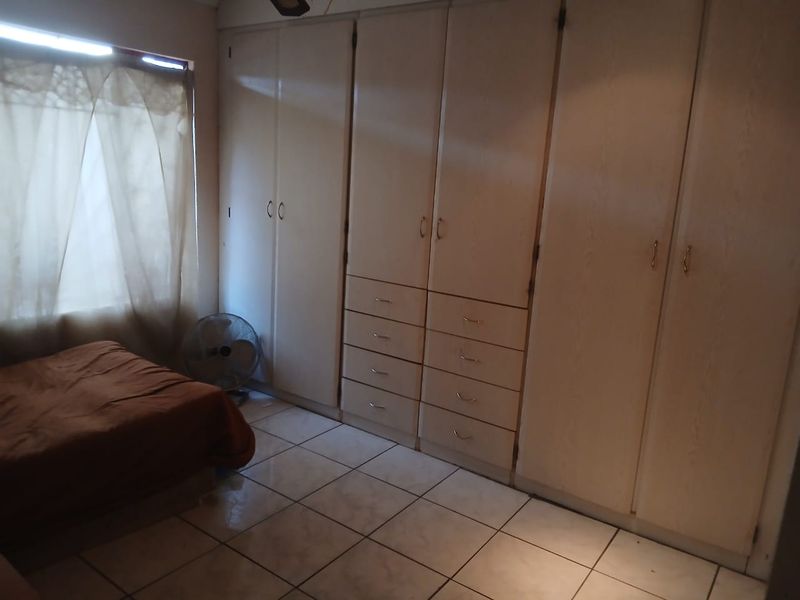 A bedroom featuring extensive built-in cupboards and tiled flooring, offering practical storage space.
