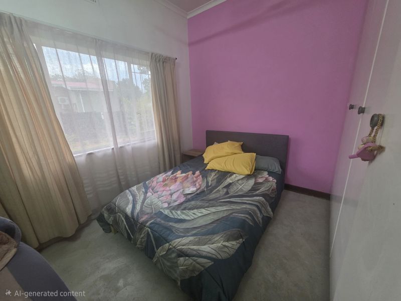 A bedroom featuring a built-in wardrobe and large window, currently finished with pink accent wall paint and requiring cosmetic updates to the flooring and walls.