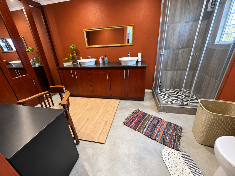 A bathroom featuring a double vanity with vessel sinks, built-in cabinetry, and a separate shower enclosure with tiled finishes.