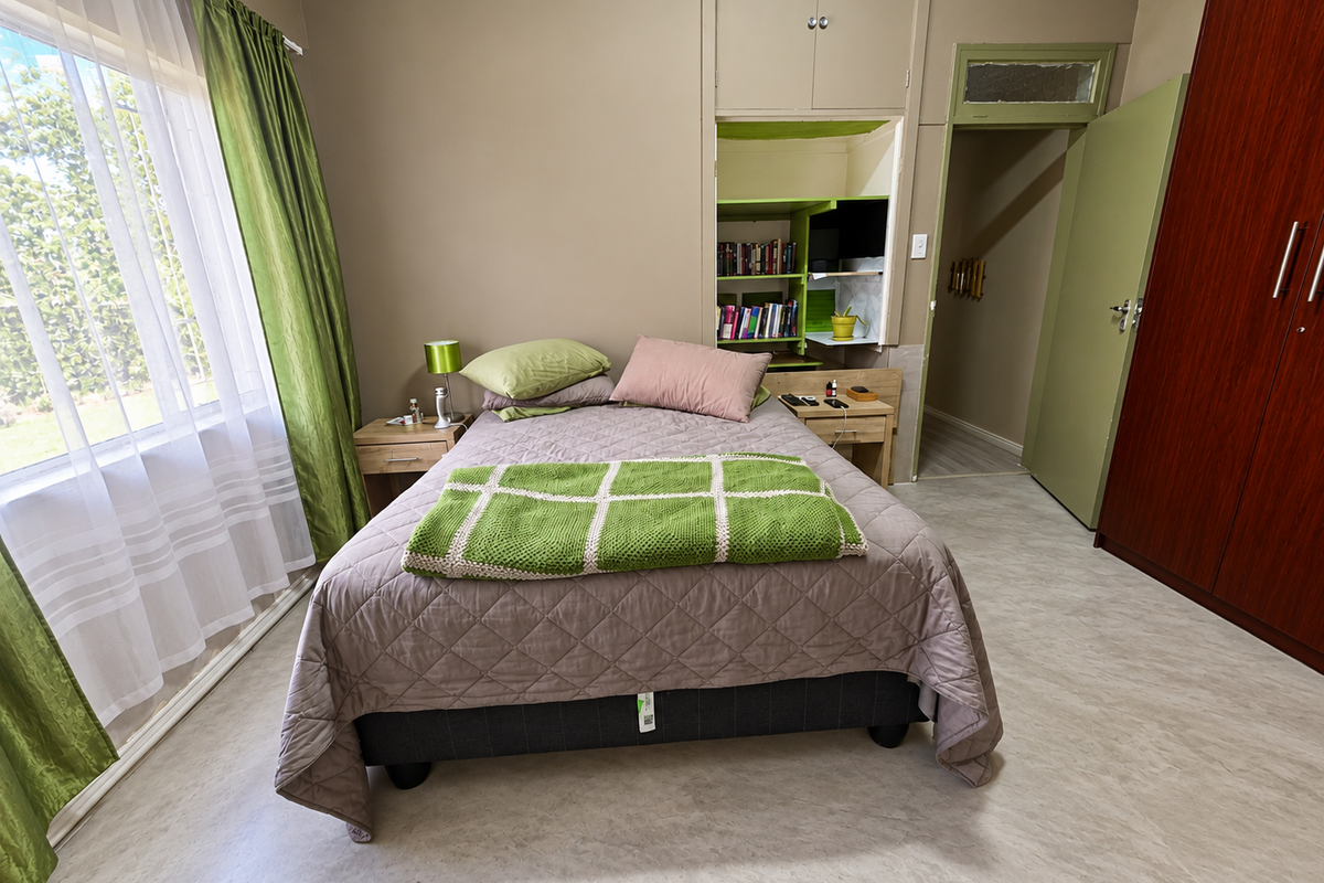 A bedroom featuring built-in cupboards, recessed shelving, and vinyl flooring, with natural light provided by a large window.