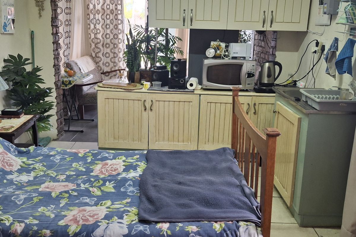An open-plan studio space featuring a compact kitchenette with built-in cabinetry and a sink, integrated into the living and sleeping area.