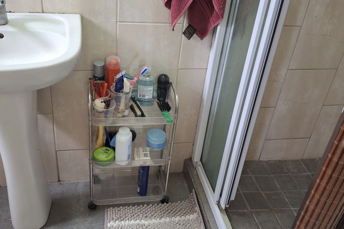 A compact bathroom featuring a pedestal washbasin and a shower enclosure with tiled wall and floor finishes.