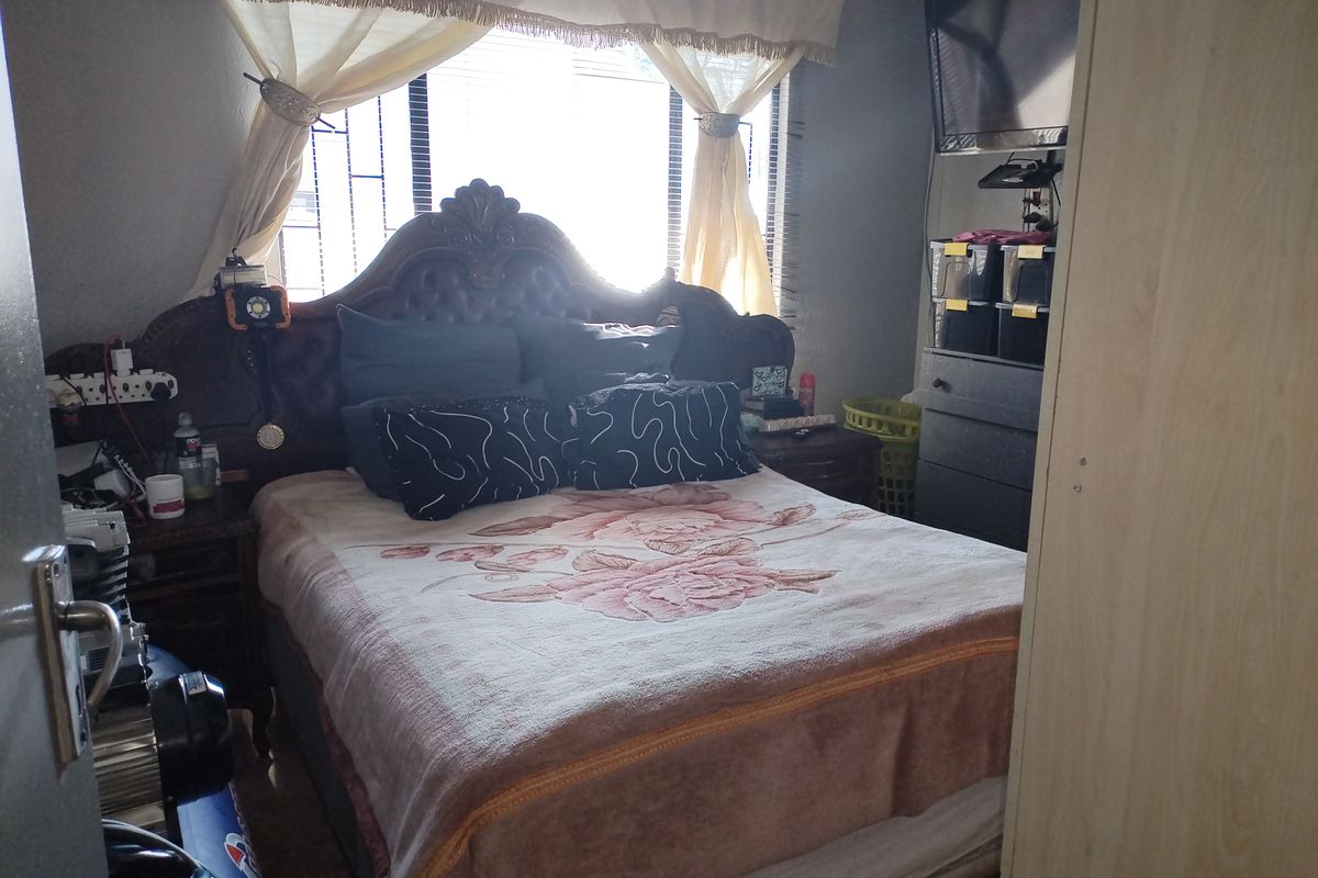 A standard bedroom featuring security bars on the window and a built-in wardrobe, providing functional sleeping space.