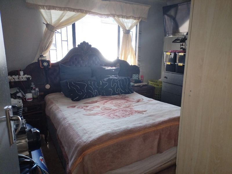 A standard bedroom featuring security bars on the window and a built-in wardrobe, providing functional sleeping space.