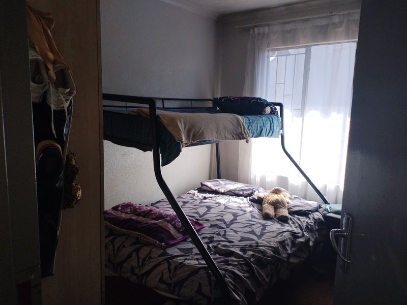 A compact bedroom featuring a window with natural light, suitable for a child or guest room.