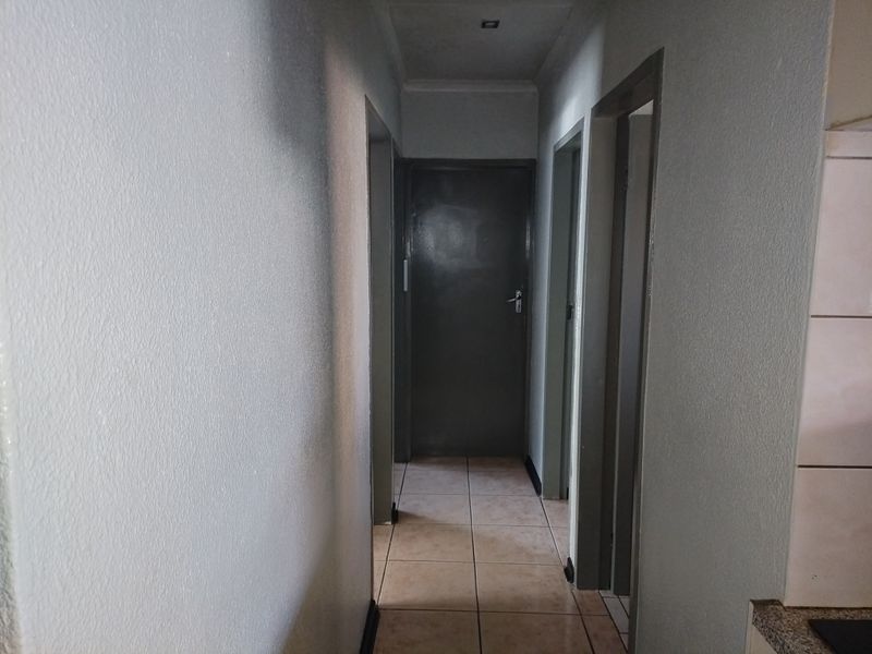 A functional interior hallway featuring tiled flooring and multiple internal doors, providing access to various rooms within the property.