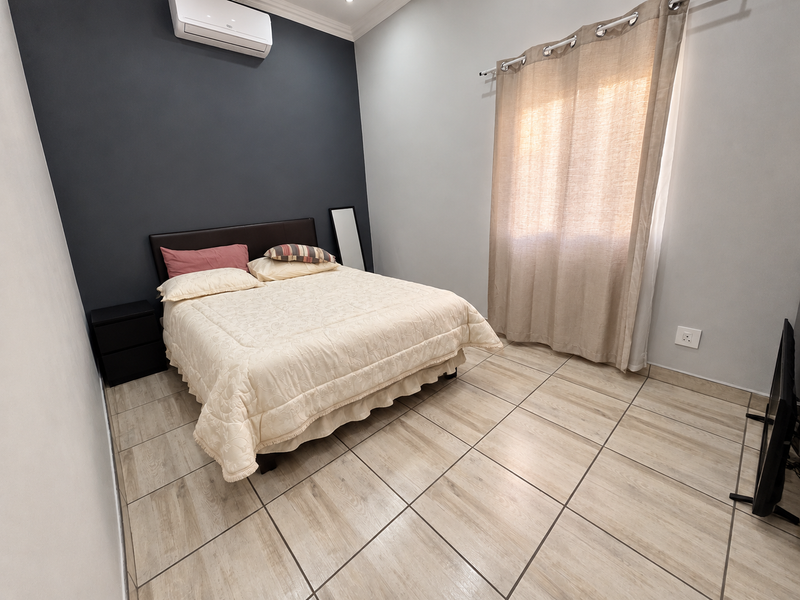 A well-maintained bedroom featuring tiled flooring, a split-system air conditioner, and neutral wall finishes.