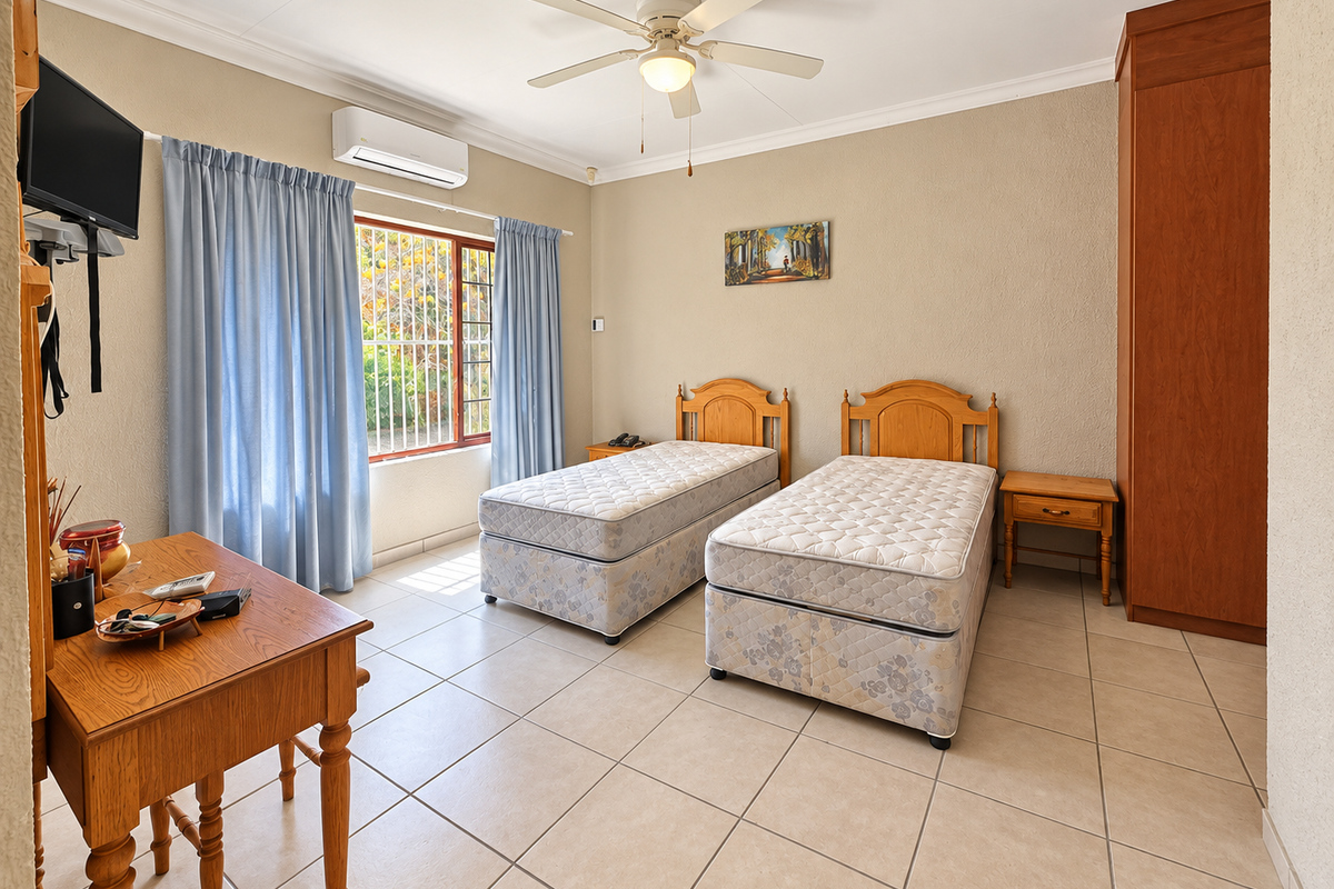A well-maintained bedroom featuring tiled flooring, a built-in wardrobe, ceiling fan, and a split-system air conditioner for climate control.