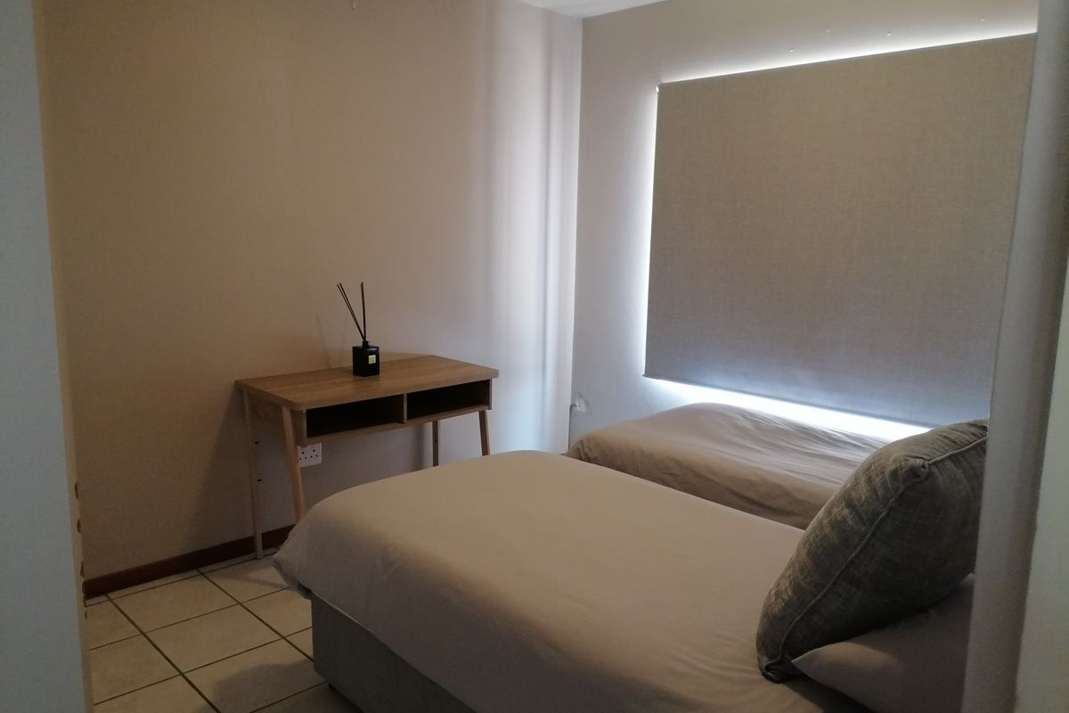 A functional bedroom featuring tiled flooring and a fitted roller blind, providing a neutral and simple living space.