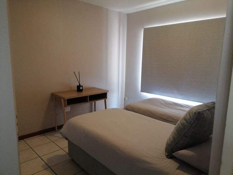 A functional bedroom featuring tiled flooring and a fitted roller blind, providing a neutral and simple living space.