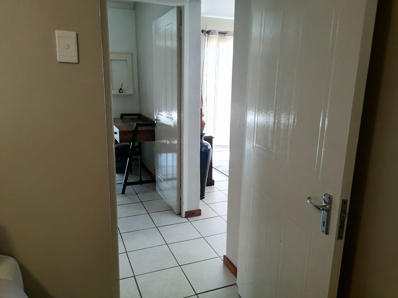 A view through a doorway into a tiled hallway connecting multiple rooms within the apartment.