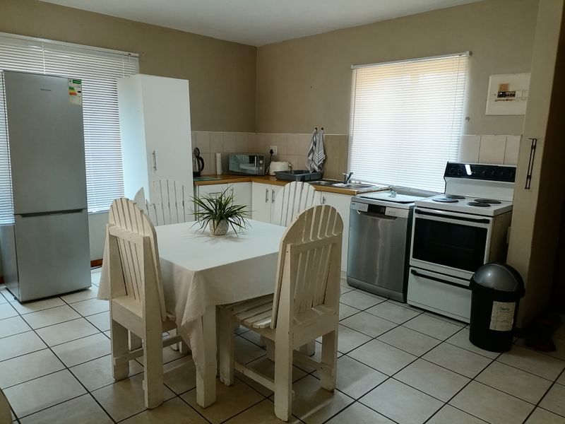 Open-plan kitchen and dining area featuring tiled flooring, functional cabinetry, and integrated appliances, providing a practical layout for daily living.