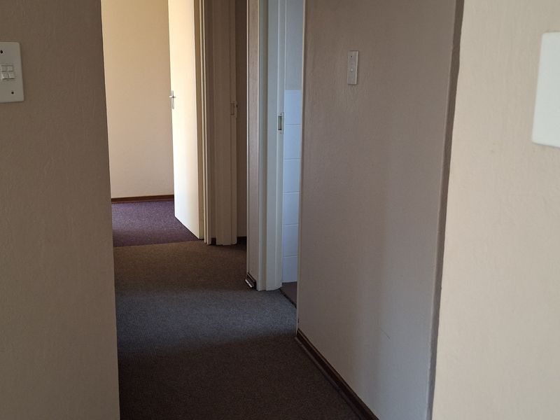 A functional hallway featuring carpeted flooring and an integrated intercom system, providing access to multiple rooms within the property.