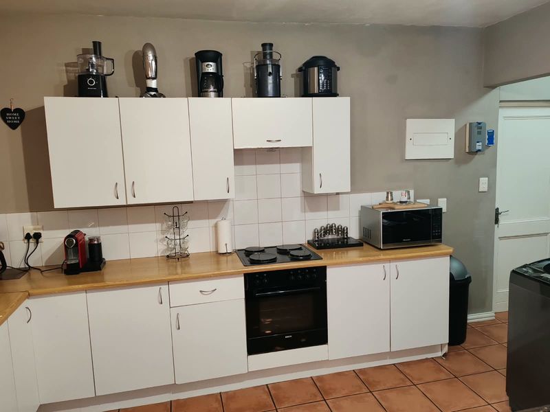 A functional kitchen featuring white cabinetry, laminate countertops, a built-in oven with electric hob, and tiled flooring.
