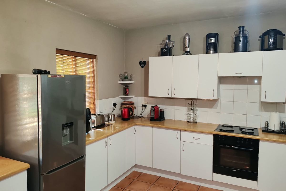 A functional kitchen featuring white cabinetry, laminate countertops, tiled backsplash, and integrated electric cooking appliances with tiled flooring.
