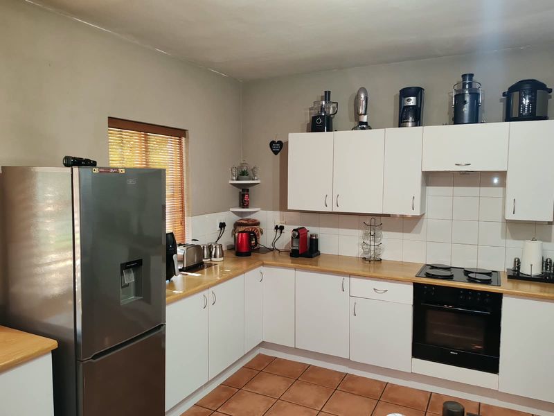 A functional kitchen featuring white cabinetry, laminate countertops, tiled backsplash, and integrated electric cooking appliances with tiled flooring.
