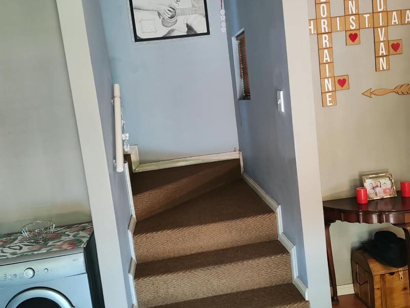 A carpeted staircase leading to an upper level, featuring a handrail and tiled flooring in the adjacent area.