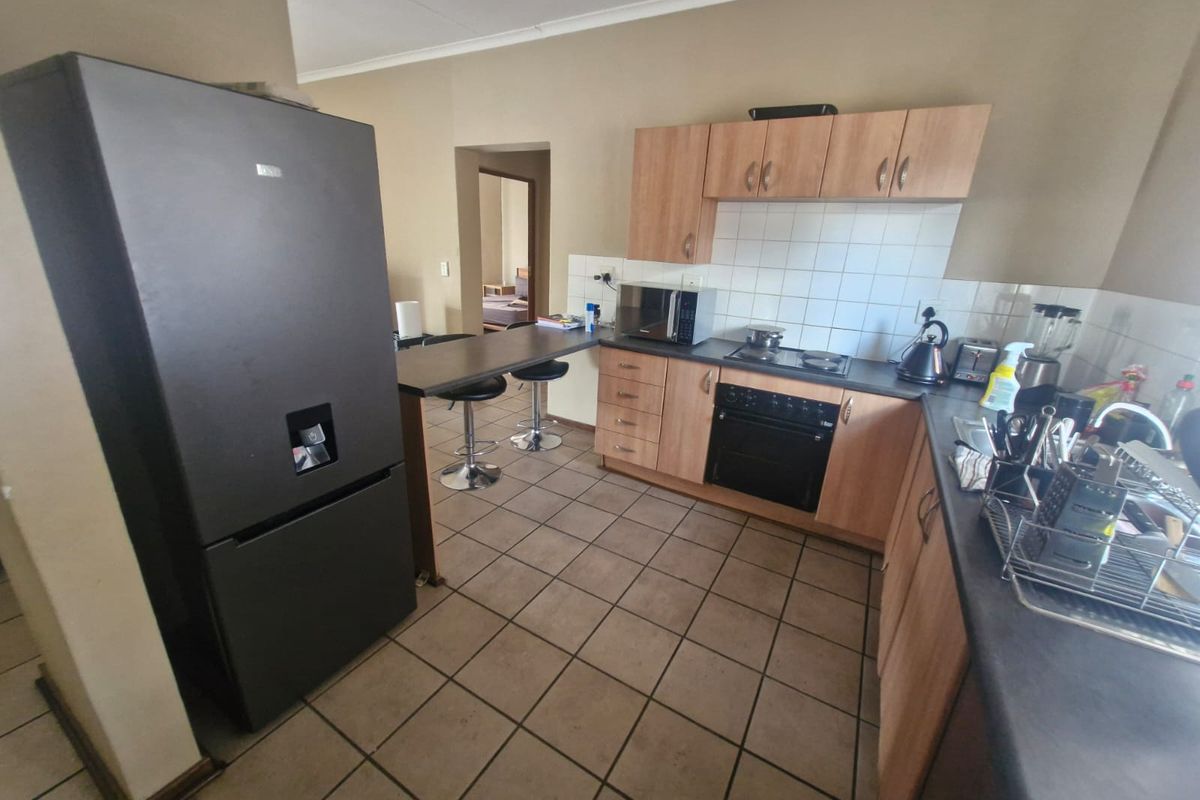 A functional kitchen featuring wood-finish cabinetry, dark laminate countertops, a built-in oven with hob, and a convenient breakfast bar area.