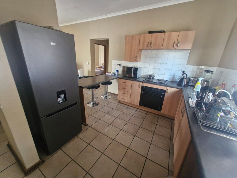 A functional kitchen featuring wood-finish cabinetry, dark laminate countertops, a built-in oven with hob, and a convenient breakfast bar area.