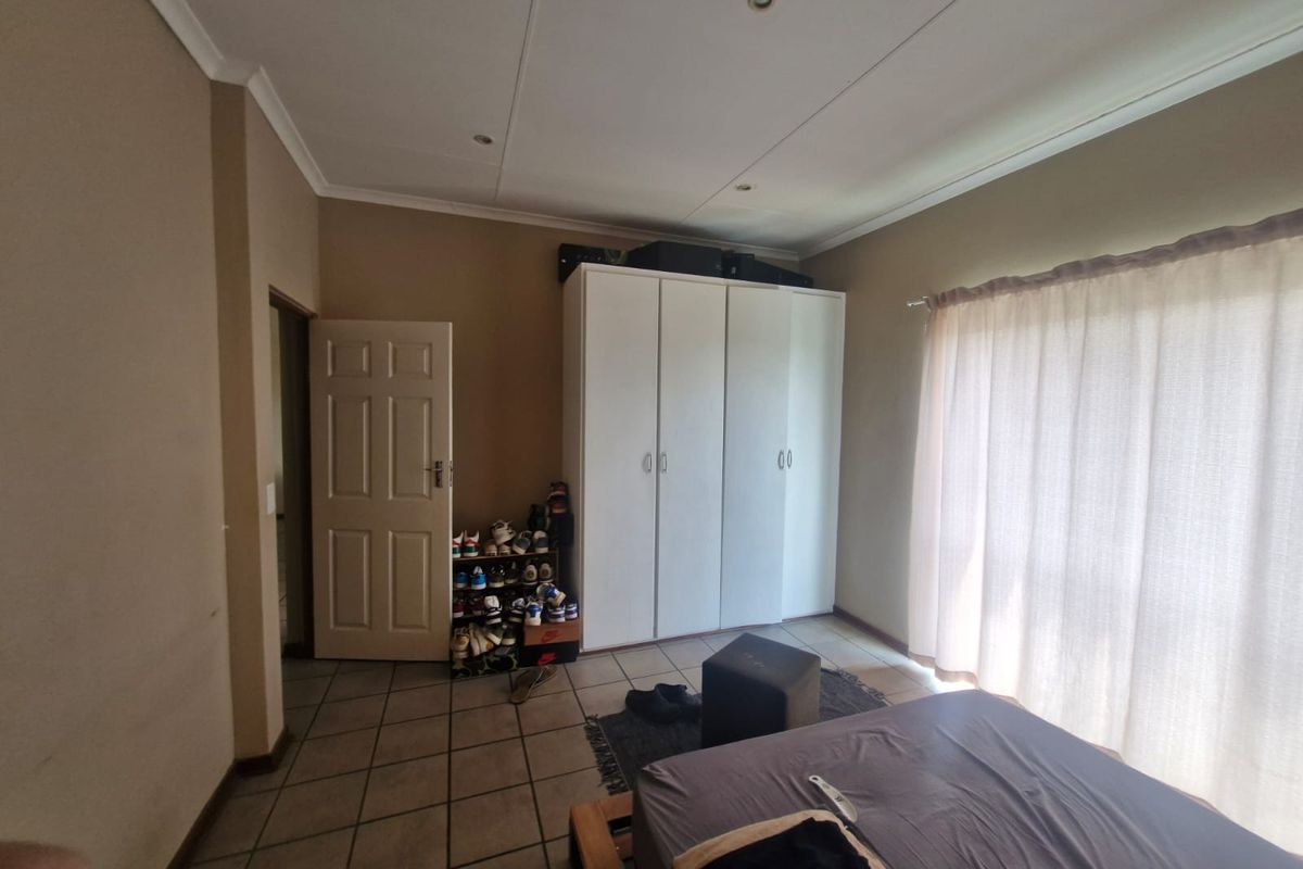A bedroom featuring tiled flooring, recessed ceiling lighting, and a built-in wardrobe, offering a functional space with neutral wall tones.