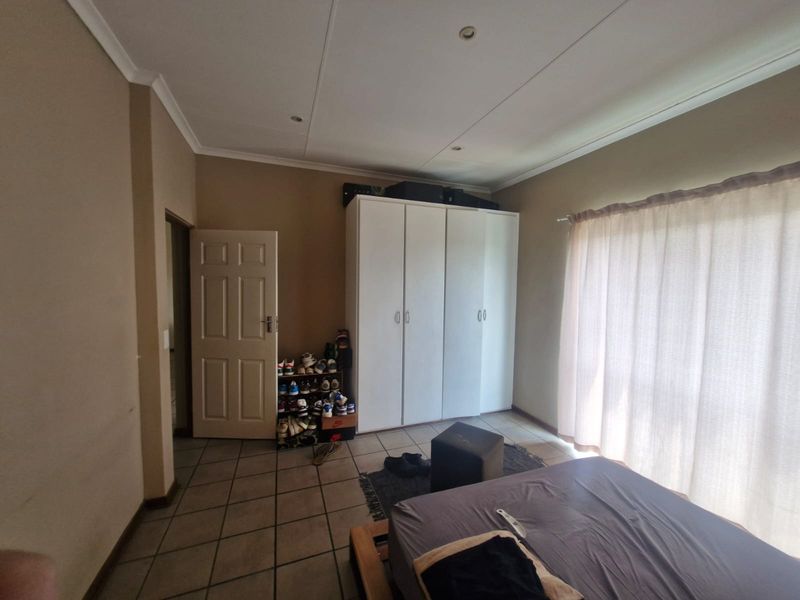 A bedroom featuring tiled flooring, recessed ceiling lighting, and a built-in wardrobe, offering a functional space with neutral wall tones.