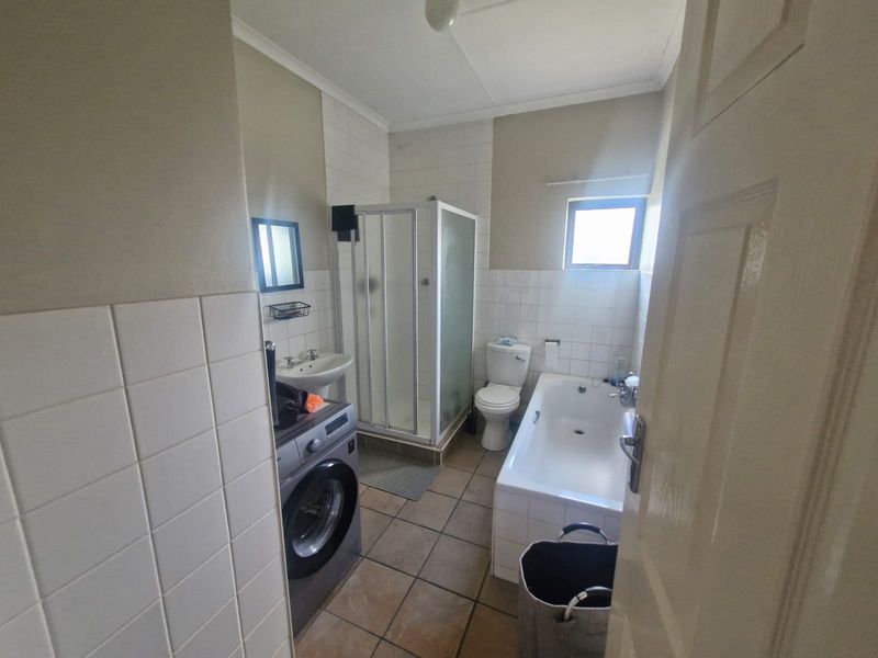 A functional bathroom featuring a shower enclosure, bathtub, toilet, and washbasin with tiled finishes throughout.