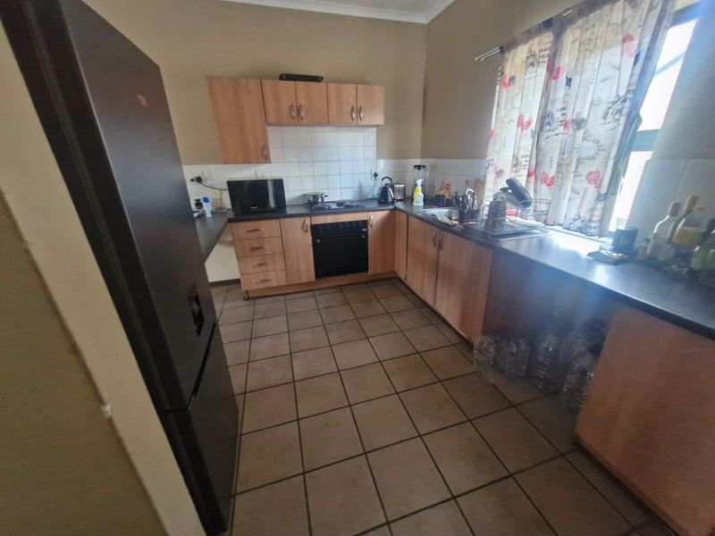 Functional kitchen featuring laminate cabinetry, built-in oven, hob, tiled splashback, and ceramic floor tiles.