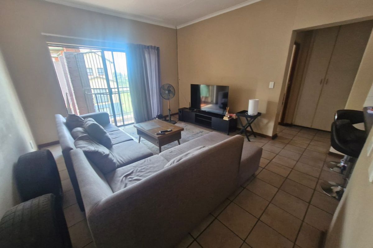 A living room featuring tiled flooring and a sliding glass door leading to an outdoor area, with adjacent built-in storage.
