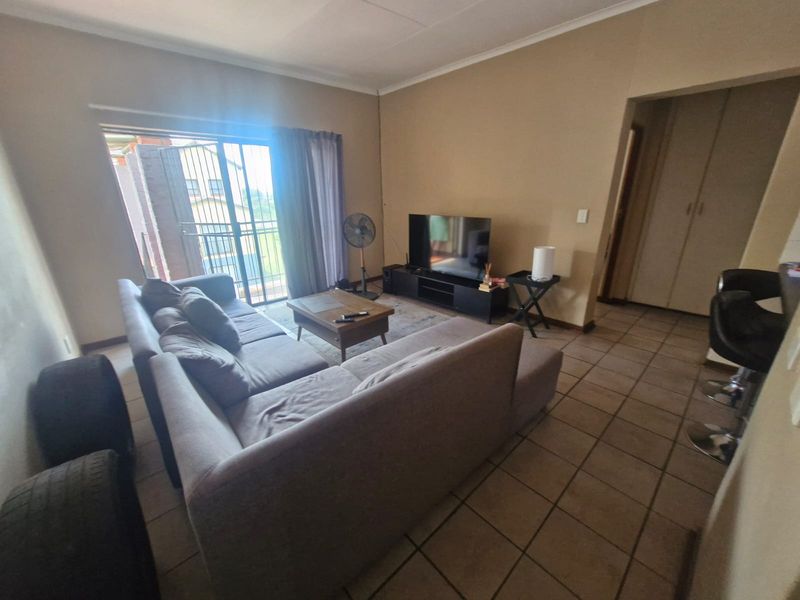 A living room featuring tiled flooring and a sliding glass door leading to an outdoor area, with adjacent built-in storage.