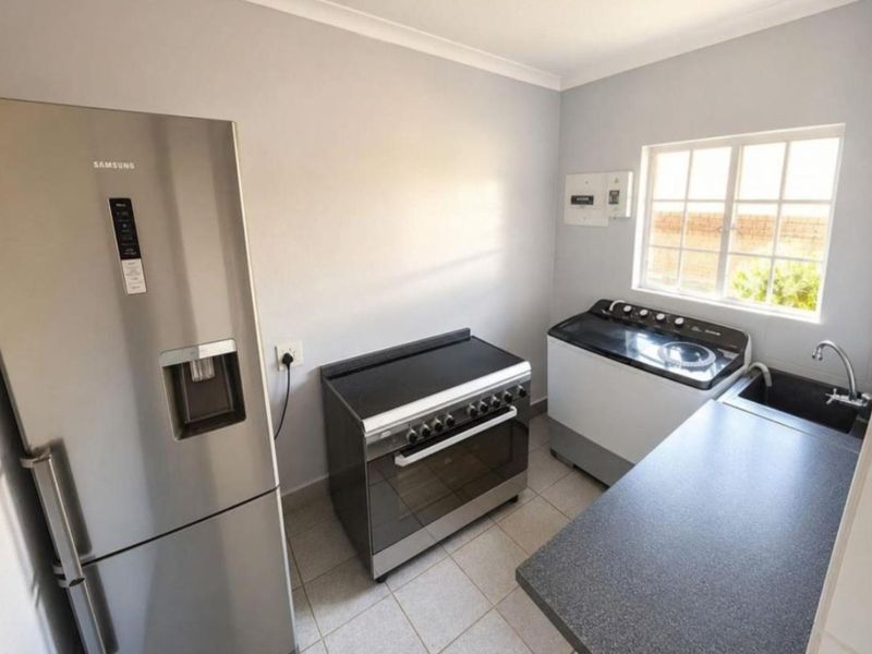 A functional kitchen area featuring tiled flooring, a built-in stove, a sink, and a window providing natural light.