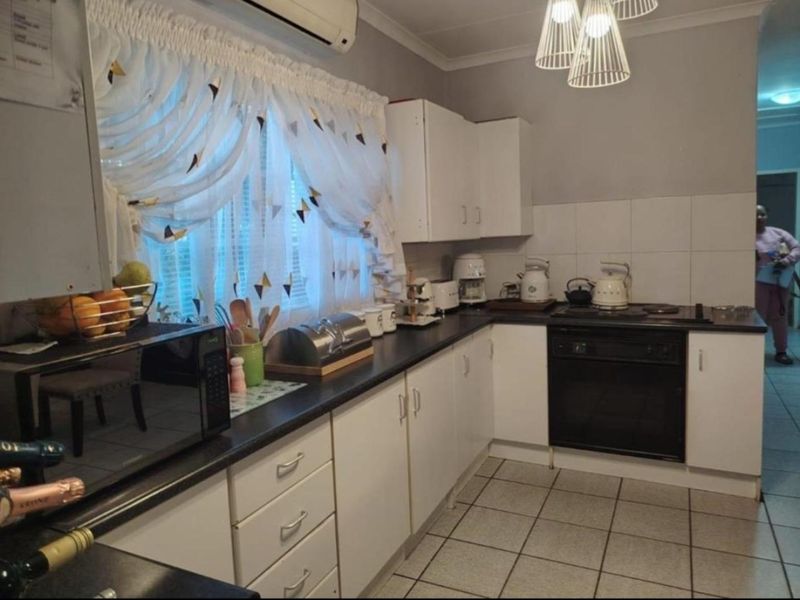 A functional kitchen featuring white cabinetry, dark countertops, tiled flooring, and a built-in oven with an electric hob.