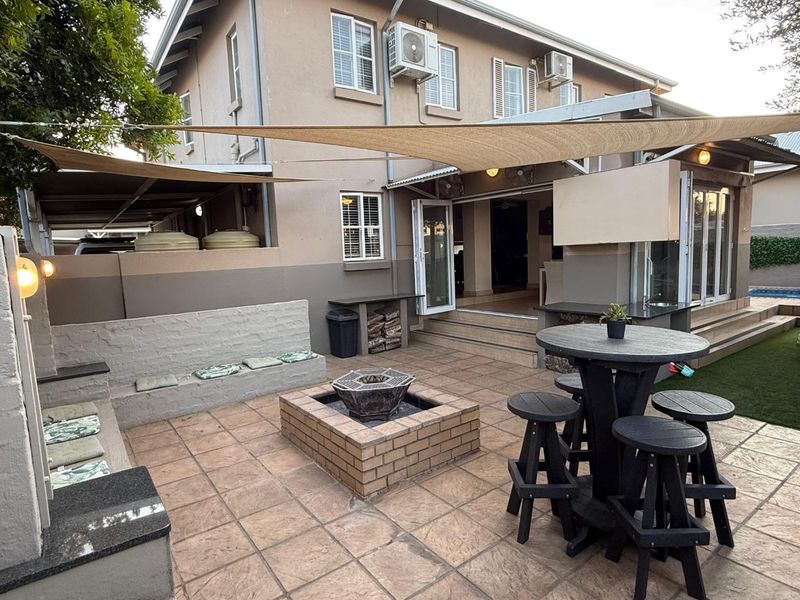 Spacious outdoor patio featuring a built-in brick fire pit, integrated bench seating, and an outdoor kitchen area, perfect for entertaining.