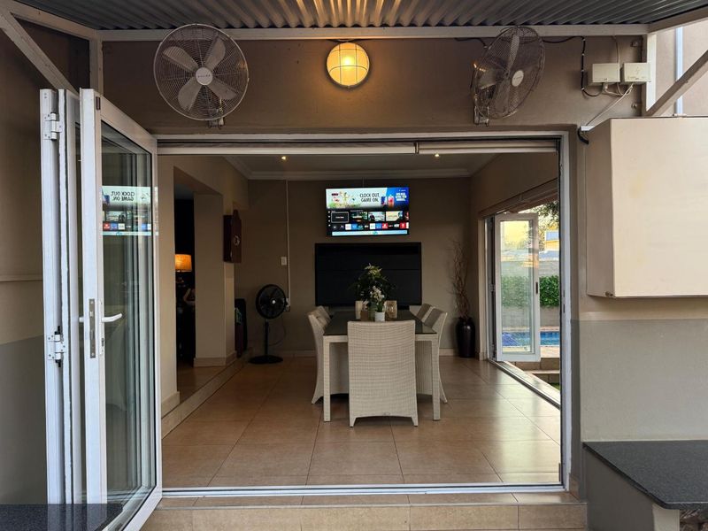 A covered patio area featuring tiled flooring, bi-fold doors, and wall-mounted fans, providing a seamless transition between indoor and outdoor living spaces.